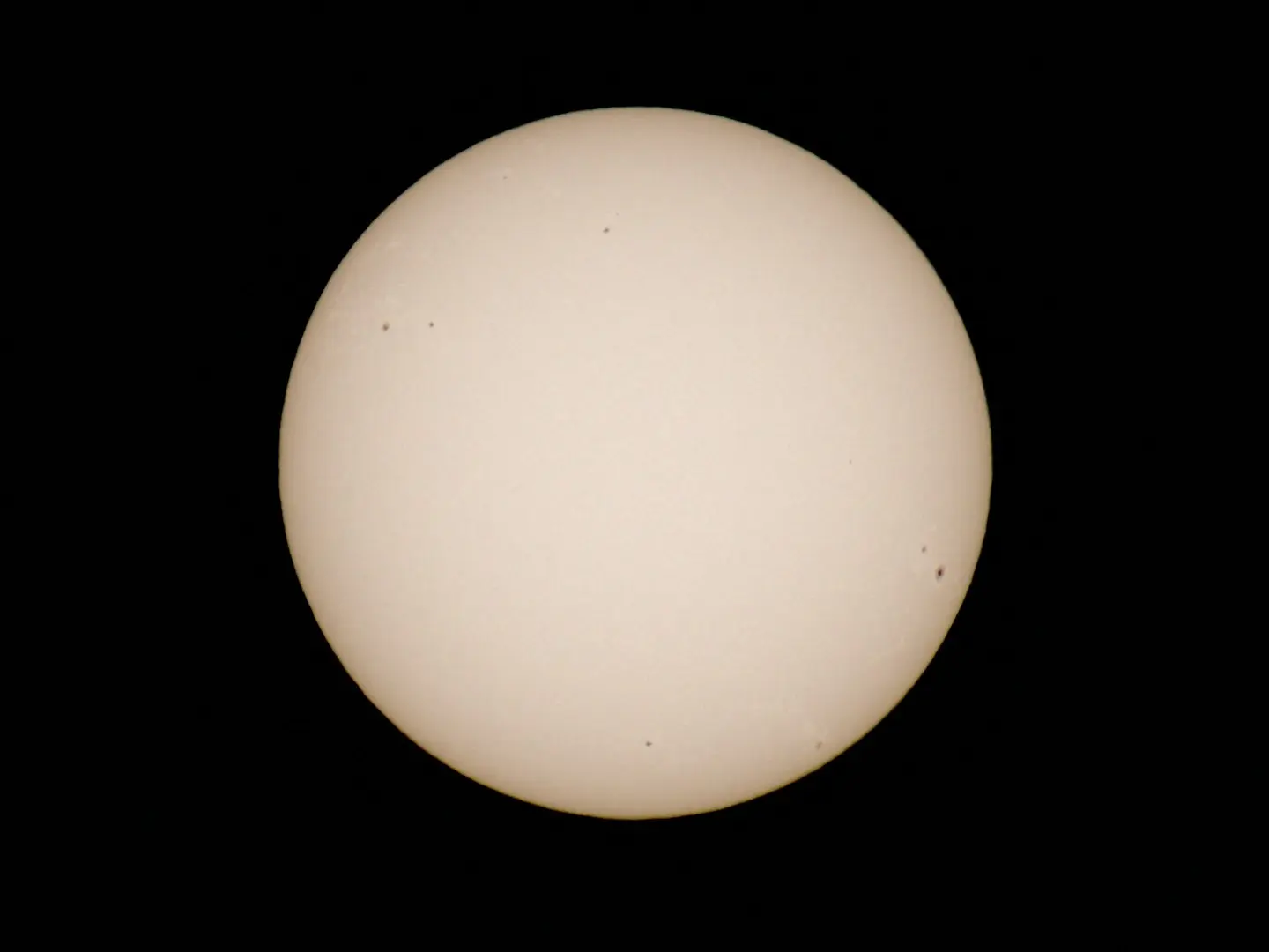 A photograph of the sun against a black background with multiple sunspots visible